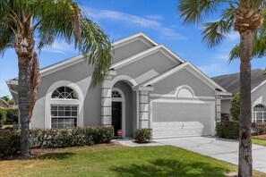 A residential house with a garage, arched windows, and palm trees in the yard. - Beautiful Glenbrook Pool Home with 4 Bedrooms & 3 Bathrooms (Clermont)