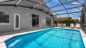 Una piscina con area coperta, acqua cristallina e confortevoli sedie a sdraio bianche.