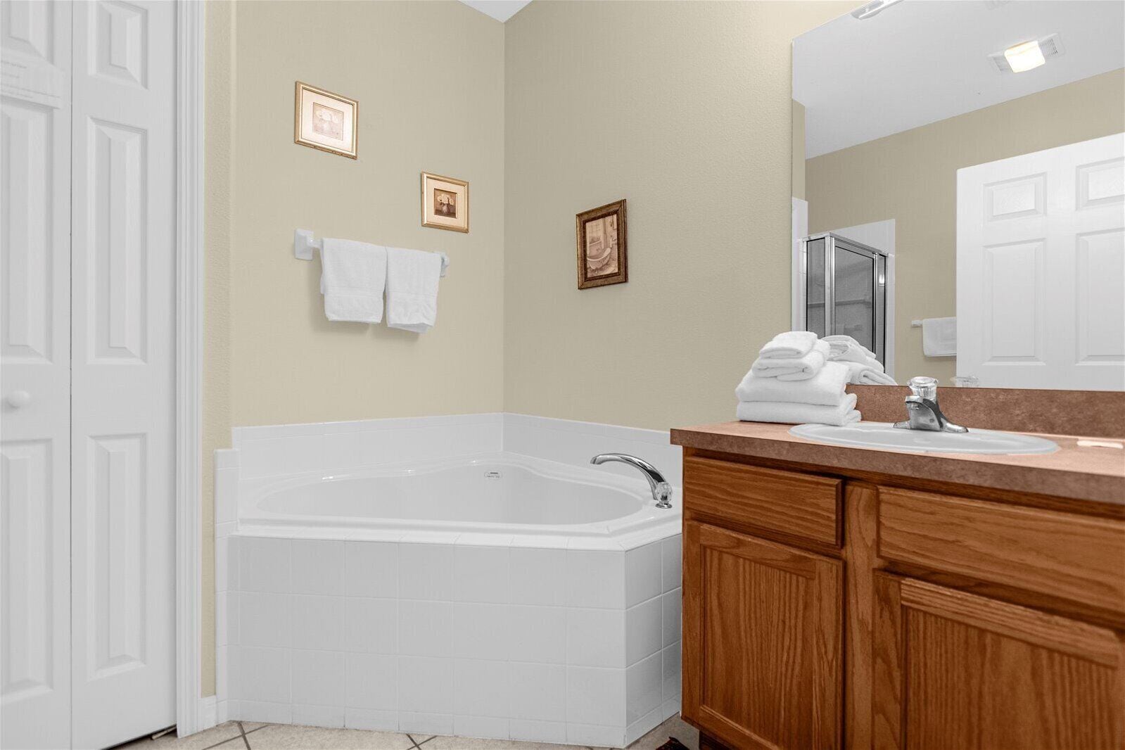 Une salle de bain avec une baignoire, un lavabo et un meuble-lavabo avec des placards en bois. Des serviettes sont accrochées au mur et un miroir est placé au-dessus du lavabo.