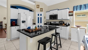 Una cucina moderna con mobili bianchi, un piano di lavoro nero e un'isola centrale con sgabelli.