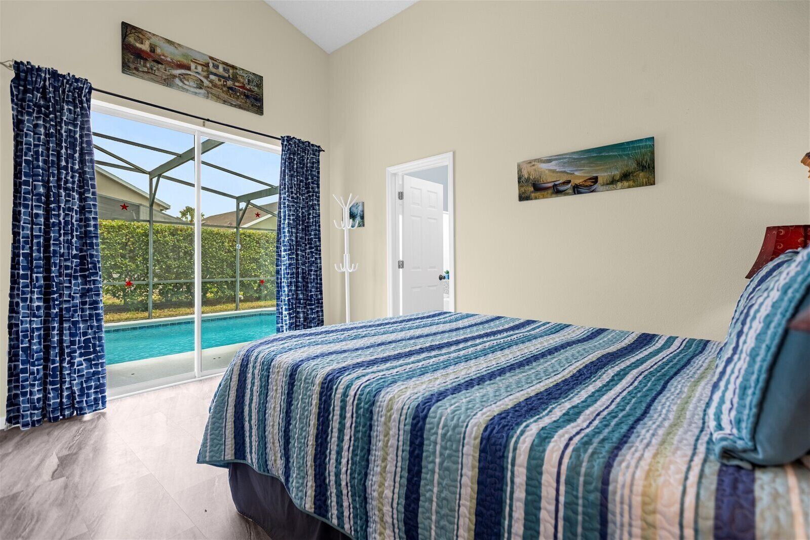 A bedroom with a large bed, a view of a swimming pool, and a door leading outside.