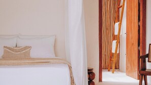 Ein Schlafzimmer mit einem Bett, einem Holzstuhl und einer Tür zu einem anderen Raum.