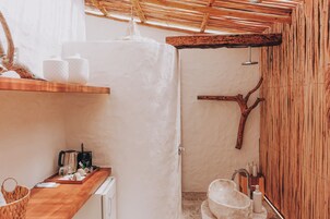 A bathroom with a wooden shower, a sink with a marble countertop, and a wooden shelf with toiletries.