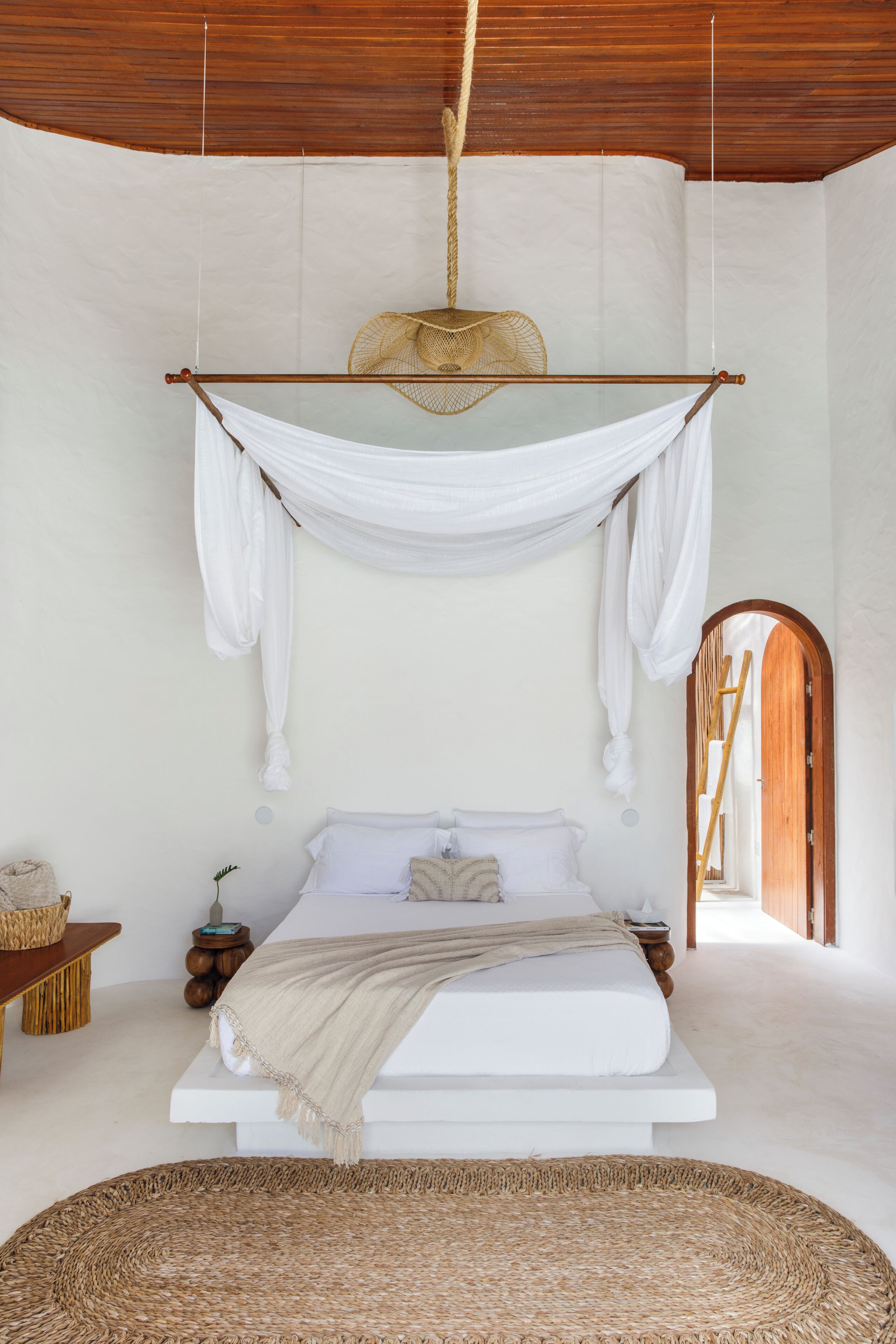 A spacious bedroom with a large bed, a hanging chair, and a wooden ceiling.