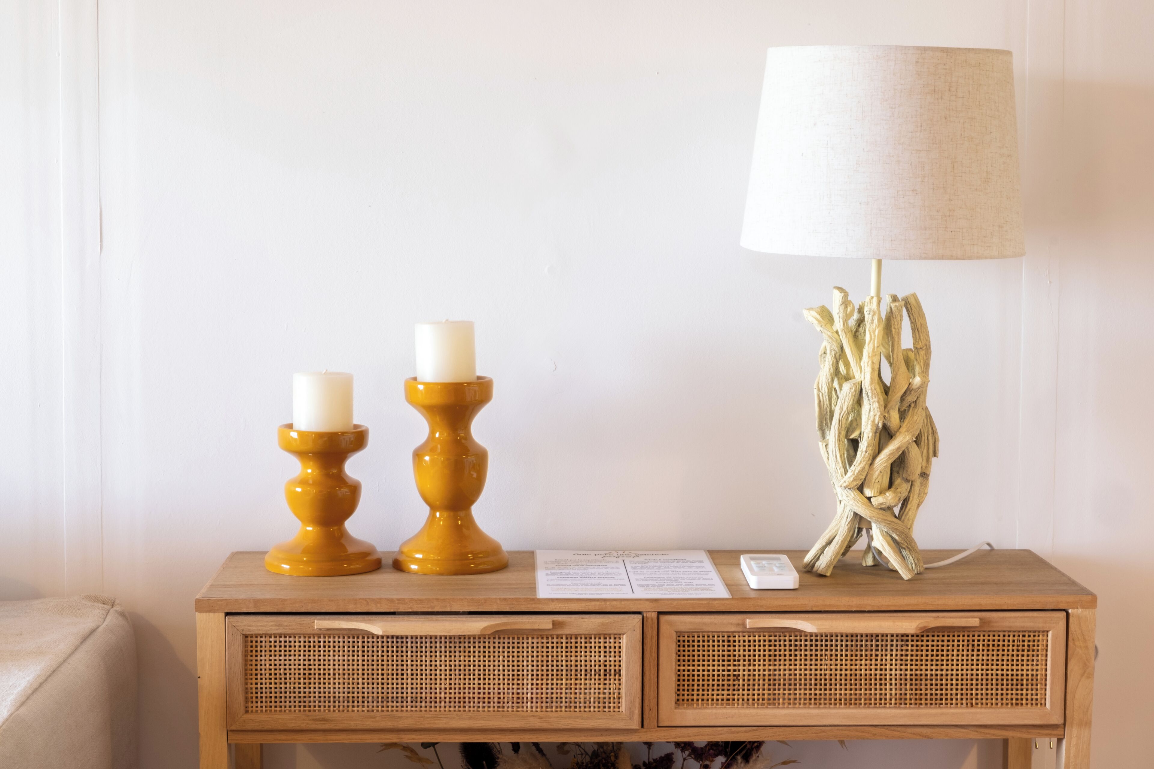 A wooden console table with two candle holders, a lamp, and a small white object.