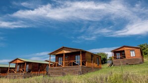 A row of wooden cabins with a porch, set against a clear blue sky. - Viña Edén (El Edén)