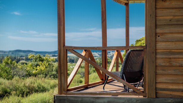 A wooden deck with a chair, wooden beams, and a view of the landscape. - Viña Edén (El Edén)