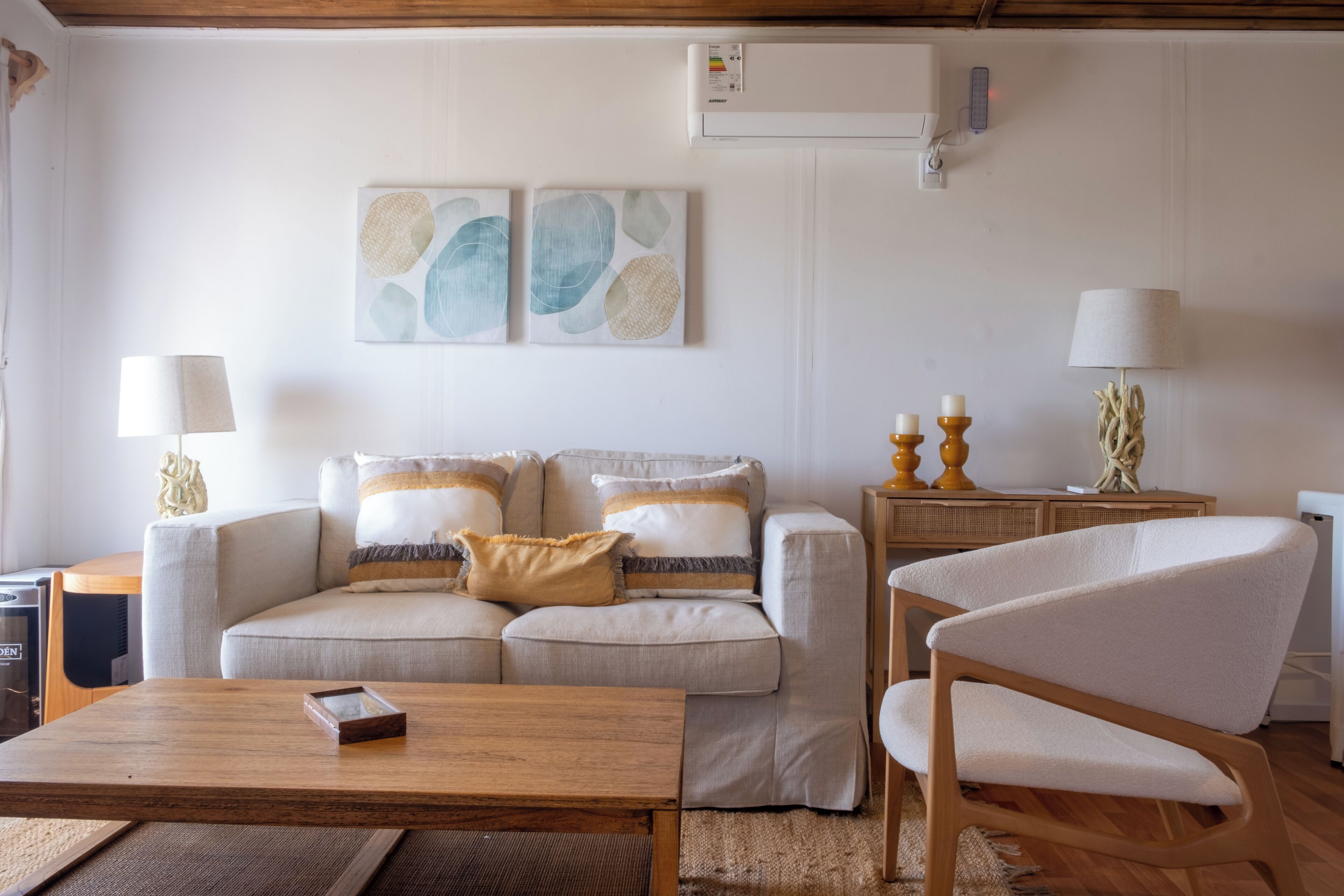 A living room with a sofa, a wooden coffee table, a chair, and wall-mounted artwork.