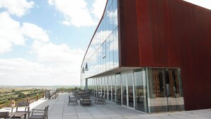 A modern building with a curved facade, large glass windows, and outdoor seating area.