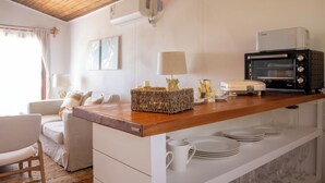 A kitchen with a wooden countertop, a built-in oven, a coffee machine, and a dining area with a sofa and chairs. - Viña Edén (El Edén)