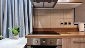 Une cuisine moderne dotée d’un plan de travail en bois, d’appareils électroménagers en acier inoxydable et d’un dosseret carrelé.