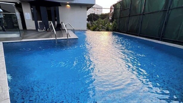 Une piscine à l’eau claire, avec un escalier en métal et une paroi en verre d’un côté.