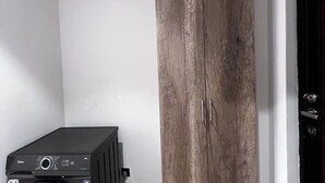 Une pièce avec un meuble de rangement noir pour les appareils électroniques, une armoire en bois et une porte noire.