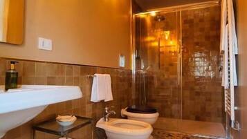 Une salle de bain avec un grand lavabo, deux toilettes, une douche et un sol carrelé.