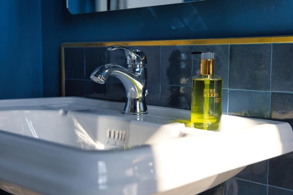 A bathroom sink with a chrome faucet and a bottle of Pure Herbs soap.