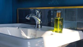 A bathroom sink with a chrome faucet and a bottle of Pure Herbs soap.