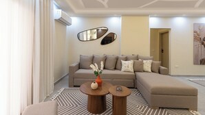Een moderne woonkamer met een modulaire bank, twee ronde salontafels en een decoratieve spiegel.