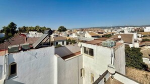 Un quartier résidentiel avec des bâtiments blancs, dont certains sont équipés d’antennes paraboliques, et un ciel d’un bleu éclatant.