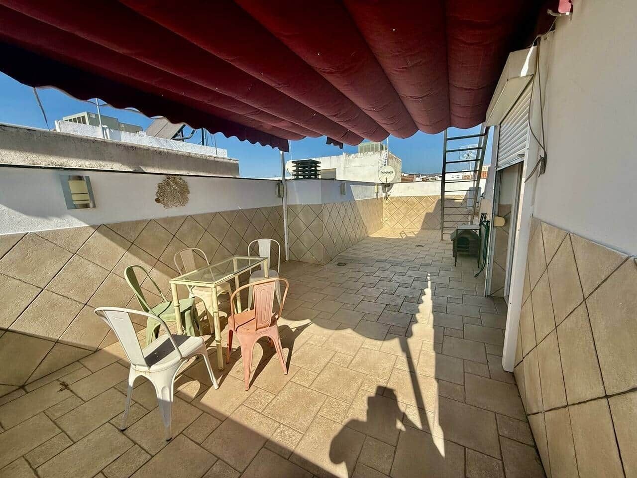 Een terras op het dak met een rood zonnescherm, een tafel met stoelen en uitzicht op de stad.