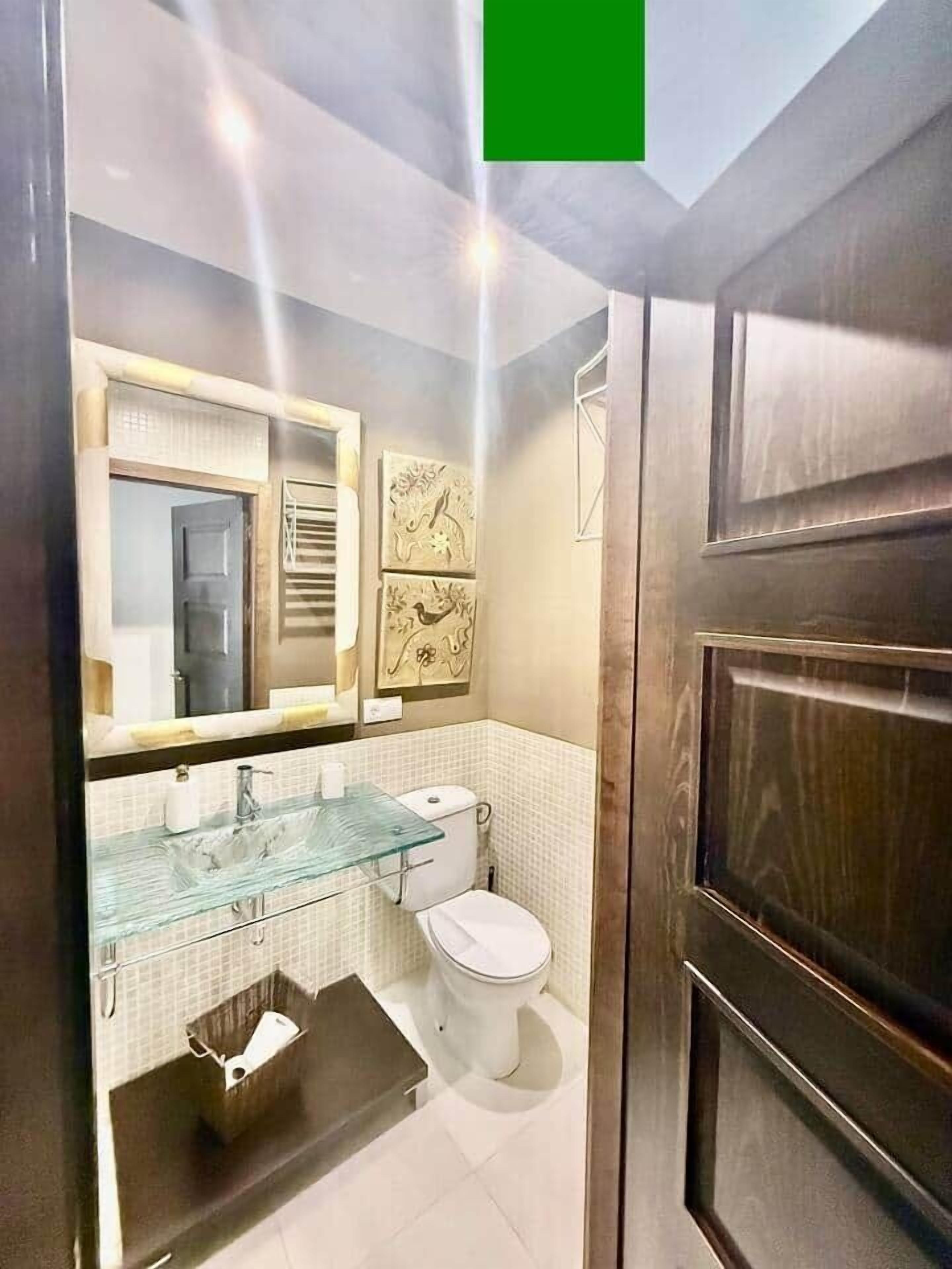 Une salle de bain moderne avec une douche à parois de verre, un lavabo en verre et des toilettes blanches.