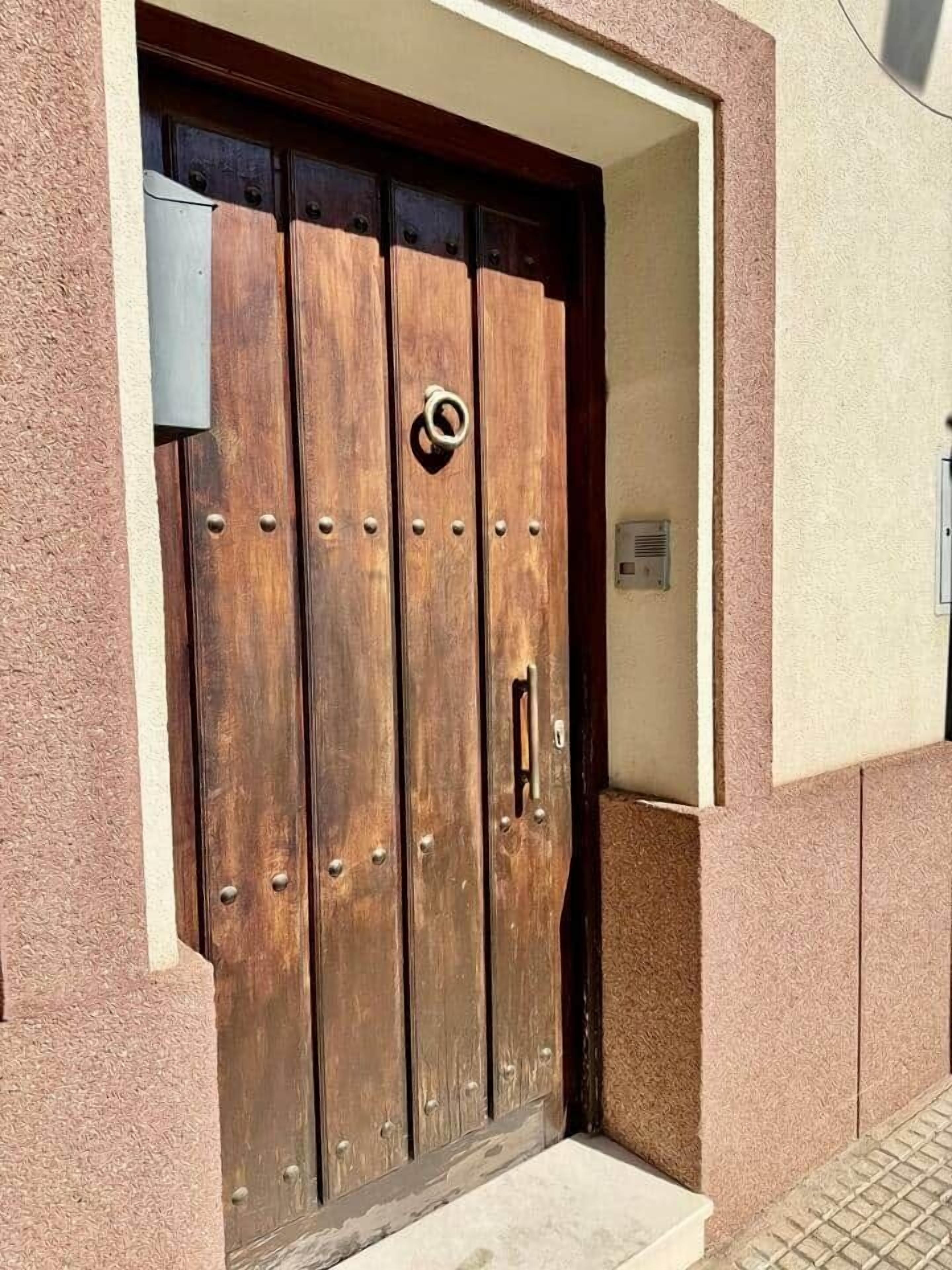 A wooden door with a metal handle and a circular metal ring.