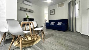 Uma sala de estar moderna com área de jantar, um sofá azul e um ventilador de teto.