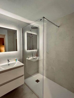 A modern bathroom with a glass-enclosed shower, a large mirror, and a white vanity with a sink. - San Luis Apartment (Córdoba)