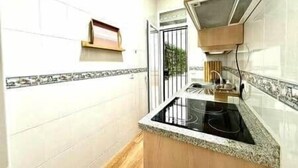 Una cocina estrecha con encimera negra, estufa y armario de madera.