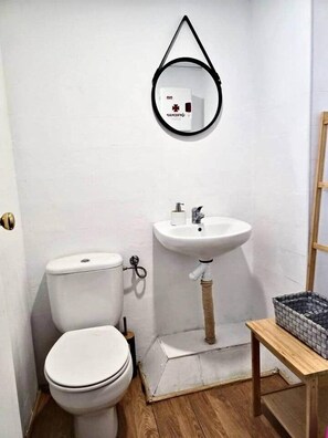 A small, white bathroom with a toilet, a sink, and a mirror. - House in La Corredera (Córdoba)