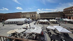 A spacious outdoor plaza with multiple white tents and umbrellas, surrounded by historic buildings with arches and tiled roofs. - House in La Corredera (Córdoba)
