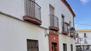 Un bâtiment à la façade blanche, à la base rouge et doté de nombreuses fenêtres avec des barreaux en métal.