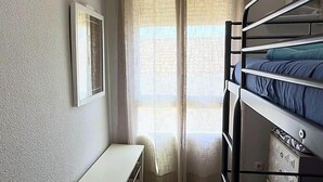 A bunk bed with a metal frame, a white desk, and a window with sheer curtains. - Apartment in Casco Historico (Córdoba)