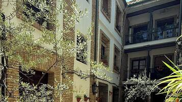 Un immeuble à plusieurs étages doté de balcons, de plantes en pot et d’une façade en briques.