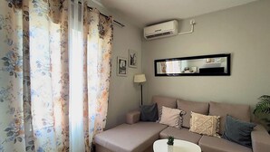 A living room with a sofa, a small table, and a wall-mounted air conditioner. - Apartment in Casco Historico (Córdoba)