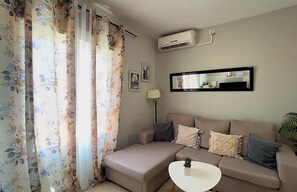 A living room with a sofa, a small table, and a wall-mounted air conditioner. - Apartment in Casco Historico (Córdoba)
