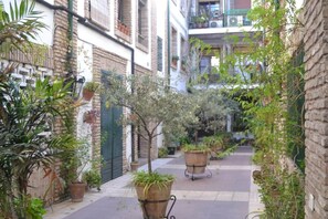 A narrow alleyway with potted plants and a brick wall on one side. - Apartment in Casco Historico (Córdoba)