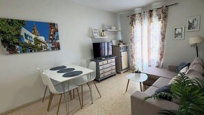 A living room with a sofa, a dining table with chairs, a TV, and a small table. - Apartment in Casco Historico (Córdoba)