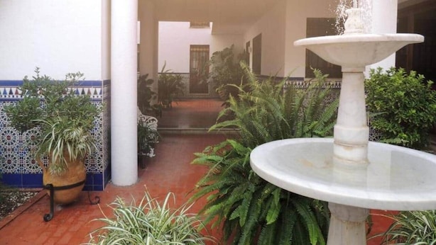 Ein Innenhof mit einem Brunnen, Kübelpflanzen und einer mit Fliesen verkleideten Wand.