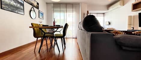 Un salon moderne avec un canapé, une table à manger, des chaises et une grande fenêtre.