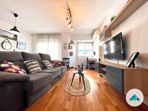 Un salon moderne comprenant un canapé, une table basse, un téléviseur et un bureau avec une chaise.