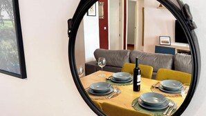 Een eetgedeelte met een ronde spiegel die een kamer weerspiegelt met een bank en een televisie.