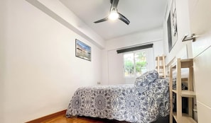 A bedroom with a bed, a ceiling fan, a window, and a door. - Centrally located urban apartment with terrace (Córdoba)