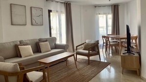 Un salon moderne comprenant un canapé, des fauteuils, une table basse et un meuble pour la télévision.