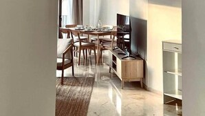 Un salon moderne comprenant un coin repas, un téléviseur à écran plat et un meuble intégré.