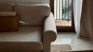 Un salon avec un canapé beige, des œuvres d’art abstraites accrochées au mur et une vue sur un balcon doté d’une balustrade.