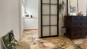 A room with a sliding glass door leading to a bathroom, a patterned bench, a dresser with a mirror, and a framed picture on the wall. - Quédate cerca del casco antiguo (Córdoba)