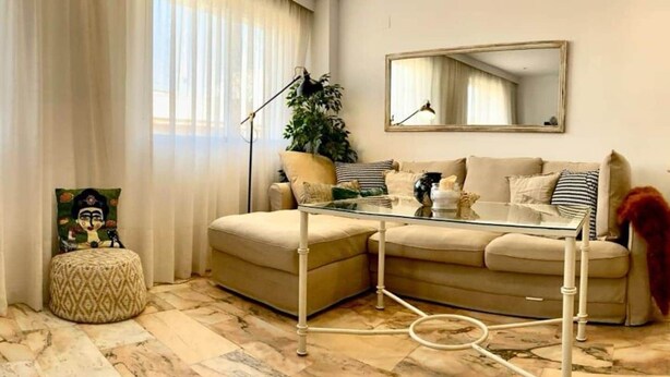 A living room with a sofa, ottoman, and a glass coffee table. - Quédate cerca del casco antiguo (Córdoba)