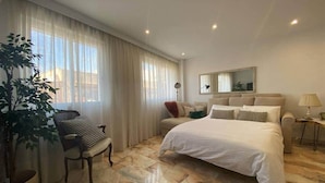 A hotel room with a large bed, a chair, a small table, and a potted plant. - Quédate cerca del casco antiguo (Córdoba)