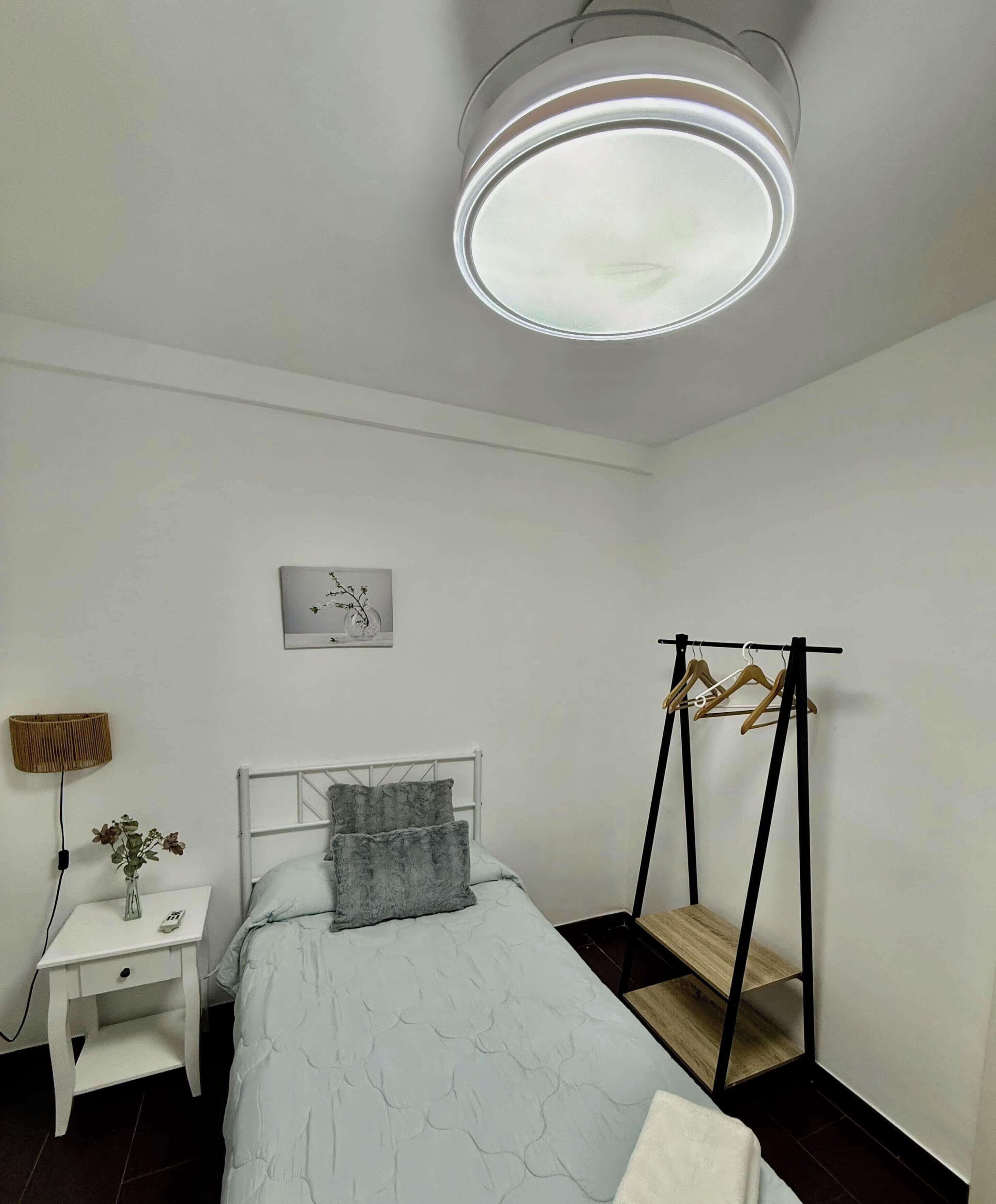 Une chambre à coucher avec un lit, une table de chevet, une lampe et un tableau accroché au mur.