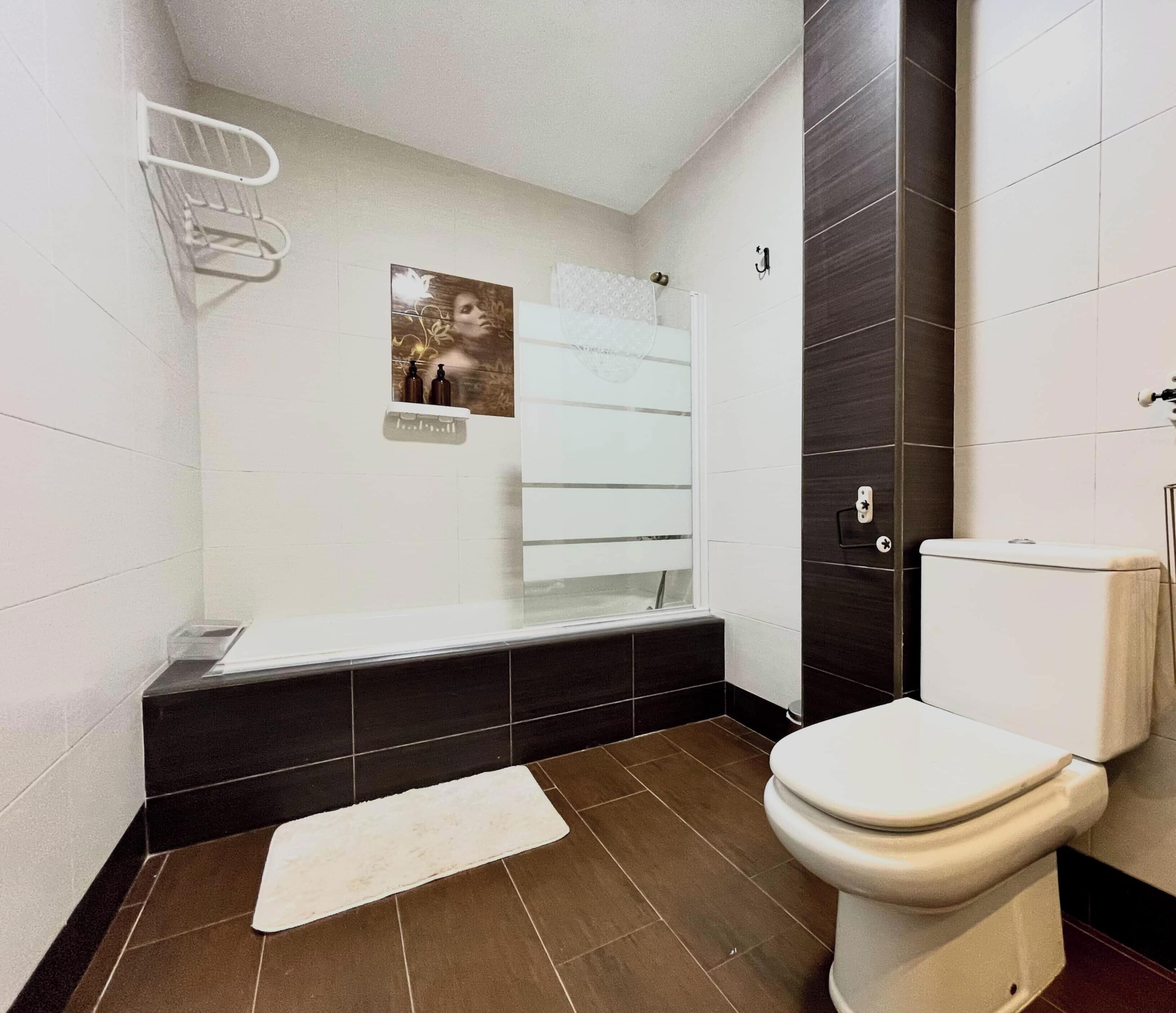 Een badkamer met een wit toilet, een bad en een douchehoek.